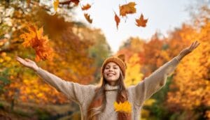 Firefly autumn shot of a young woman with a girl with a knitted hat on her head throwing leaves int