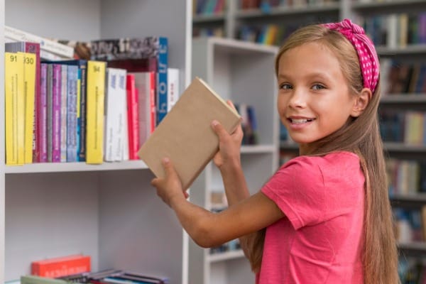 girl putting back book shelf