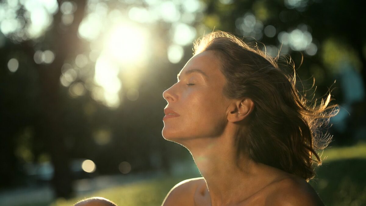 Femeie stând la soare într-un parc, simbolizând sursa naturală de vitamina D
