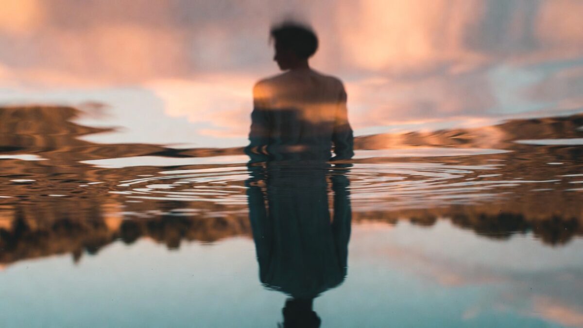 O persoană privind într-un lac ca intr-o oglindă